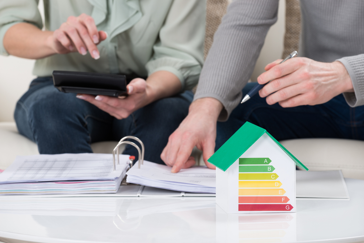 Personen zeigen auf Energieausweis-Ordner und Modellhaus